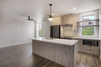 A modern kitchen with a wooden floor and a black refrigerator at The Avenue Lofts Golden Apartments, Golden, CO, 80401